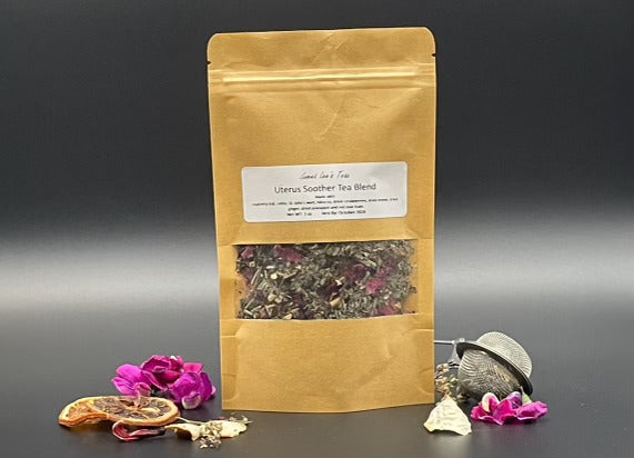 A kraft paper bag of Uterus Soother Tea Blend with dried raspberry leaf, hibiscus, nettle, and ginger, surrounded by dried flowers and citrus, highlighting its natural herbal ingredients.